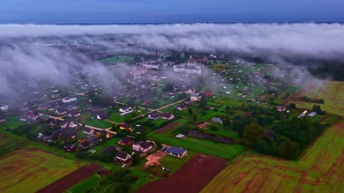 Rural village and farmland with fog in morning light, aerial