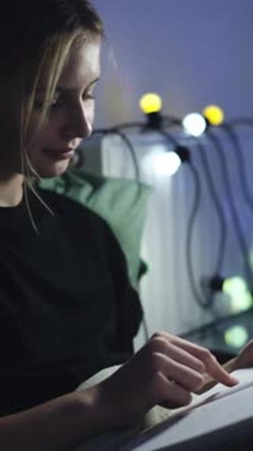 Young Adult Woman Uses Tablet in Dark Room