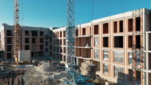 Grúa de construcción y edificio de ladrillo sin terminar en un día soleado Una grúa que opera cerca de un edificio de varios pisos
