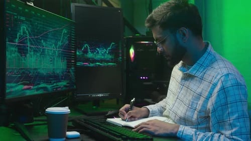 Indian Arabian Man Looking Monitor Computer Chart Graph Trading Online Typing Pc Writing Notes