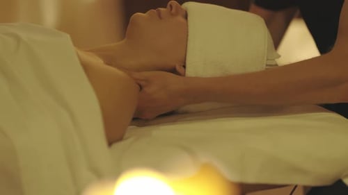 Eine entspannte Frau mit einem Handtuch über den Augen wird in einem Spa-Salon massiert und massiert den Hals und
