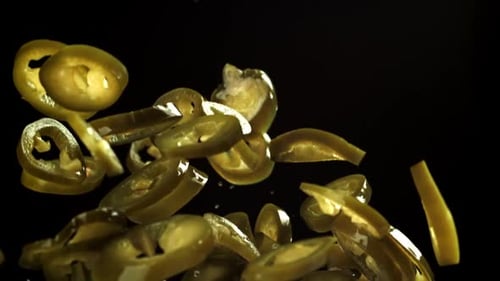 Les jalapenos marinés volent et tombent sur fond noir filmés par une caméra haut débit à 1000 images par seconde