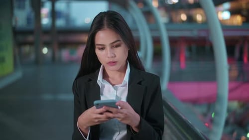 Eine junge schöne Geschäftsfrau benutzt ein Smartphone in der Stadt über Ampeln