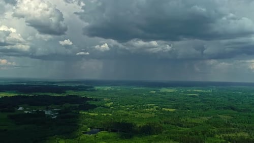 Aerial view of a lush landscape under the dramatic sky of an approaching storm