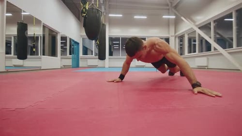 A Young Muscular Man with a Naked Torso is Training in the Gym and Doing Pushups From the Floor with