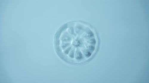 Natural Water Splashing Rings and Ripple Top View Clear Drop of Cosmetic Essence Serum Falling in