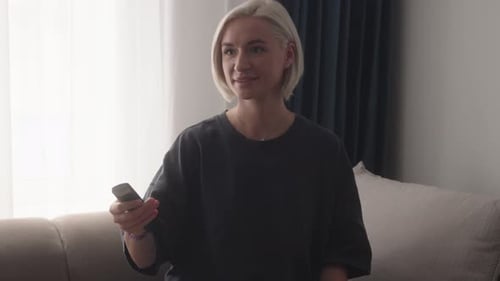Young Woman Using Remote Control on Couch
