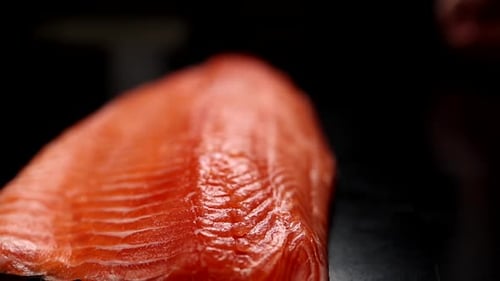 Der Koch hält ein Lachsfilet in den Händen