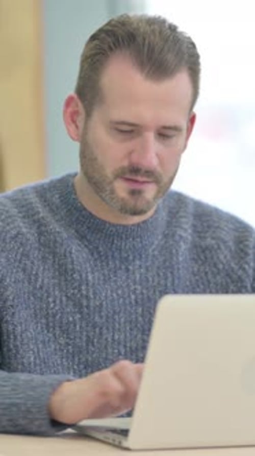 Man Works on Laptop and Smiles at Camera