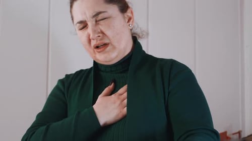 Individual Clutching Chest with Distress Woman at Home Shows Signs of Heart Trouble Woman Exhibits
