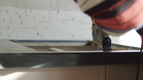 Worker Cutting Kitchen Countertop with Electric Grinder