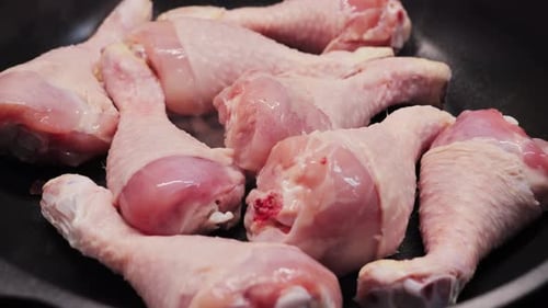 Raw chicken drumsticks resting in a pan