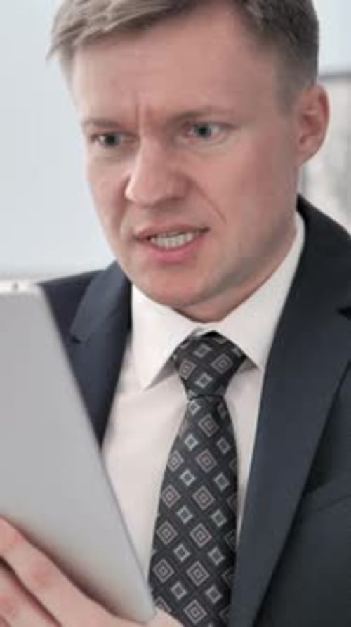 Frustrated Businessman Looking at Tablet in the Office