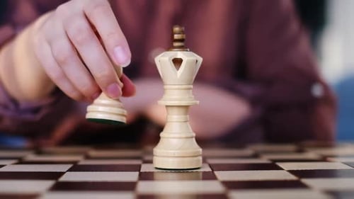 La mano de una mujer reemplaza cuidadosamente a una reina con un peón en el tablero de ajedrez, una estrategia deliberada