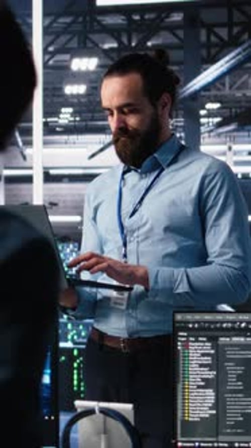 Un técnico de centro de datos de vídeo vertical utiliza un portátil para supervisar la IA LLM de redes neuronales