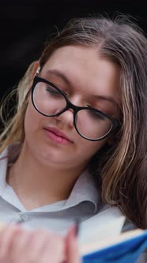 Lady With Glasses Focused on Reading While Turning to New Page