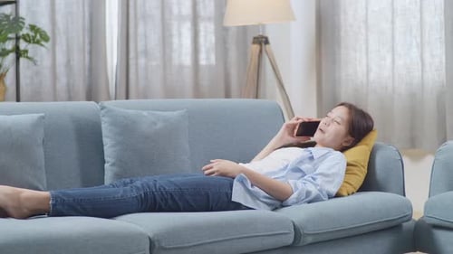 Young Adult Lying on Sofa Talking on Phone