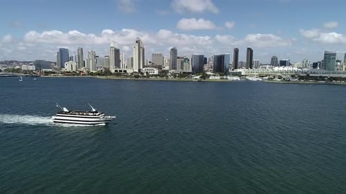 Touristisches Bootssegeln mit der atemberaubenden Skyline einer Küstenstadt im Hintergrund.