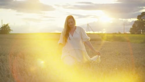 At Sunset a Woman Walks Through a Wheat Field