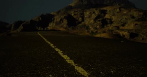 Road Through Rocky Terrain Under Night Sky with Distant Mountain View