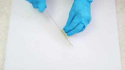 Chef Hands Slicing Garlic on White Kitchen Board