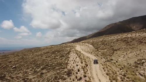 Drone : vole derrière une voiture à travers une gorge dans les montagnes du Kirghizistan