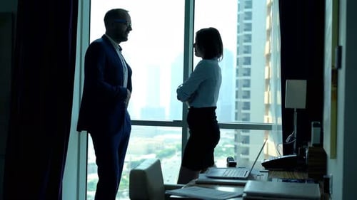 Young businesspeople relaxing and chatting by office window with city view