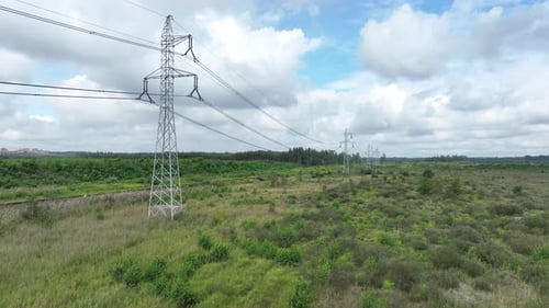 La photo prise par Drone montre une ligne à haute tension qui traverse une prairie ouverte.