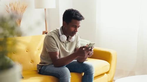 Black Man Using Smartphone in Living Room