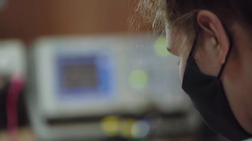 Una mujer con una máscara protectora analiza las señales eléctricas en un laboratorio de osciloscopios