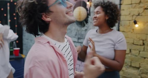 Portrait of Carefree Guy Dancing Celebrating Holiday with Friends Enjoying Music in Terrace Cafe