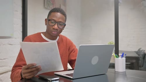 Young Man Reviews Documents at Desk