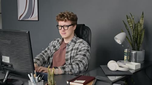 Portrait of Smiling Man with Glasses Programming on Computer
