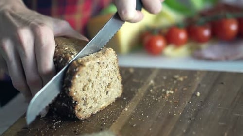 Closeup Shot Of Female Hands Slicing Whole Grain Bread
