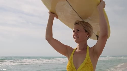 Woman surfer with surfboard goes along ocean beach.