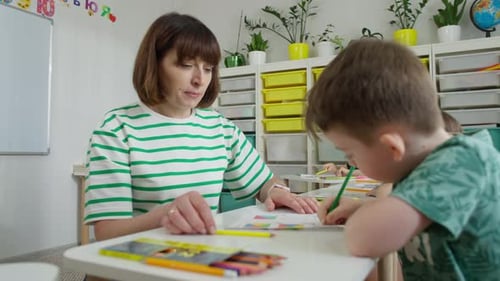 Teacher Helping Children Drawing in Classroom