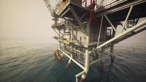 Old Oil Platform Standing in Calm Waters with Hazy Skies at Dawn