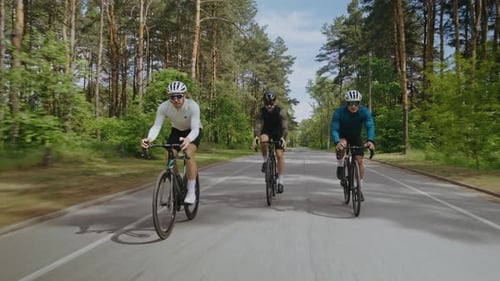 Professional Sportsmen in Helmets Ride Bicycles Along Empty Road