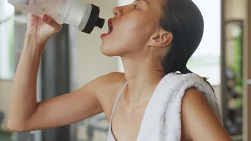 Asian fitness sport woman drink water stand on fitness gym.