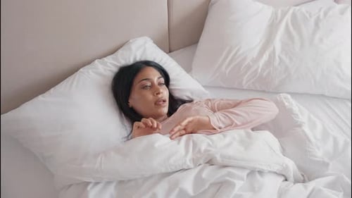 Top View of Young Woman Stretching Arms in Bed Waking Up After Good Sleep