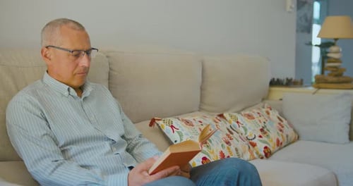 Man Reading Book on Sofa at Home