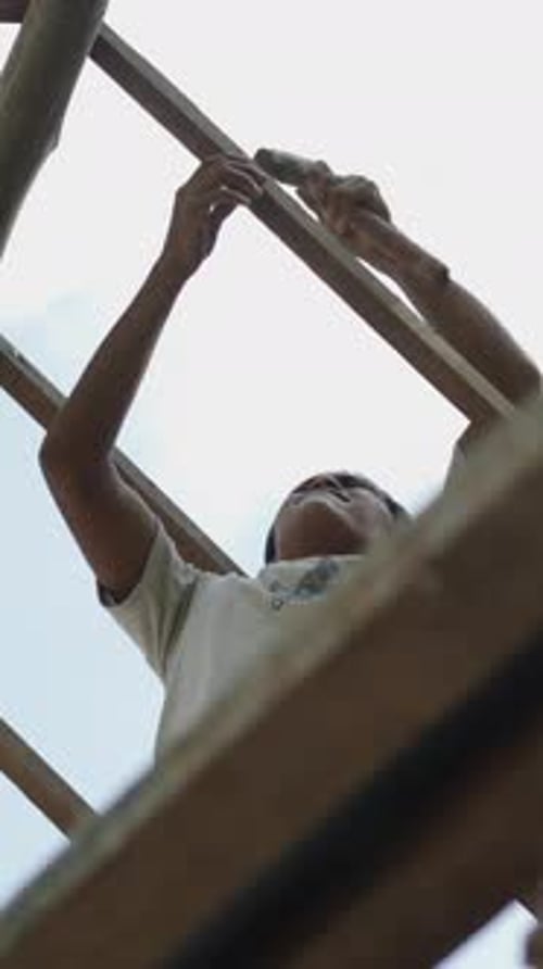 Low View of Young Asian Man Using a Hammer to Create a Roof FHD Vertical Video
