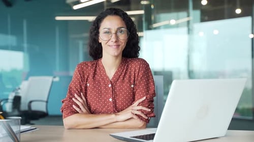 Portrait of a young happy businesswoman sitting at a desk at a workplace in a modern business office