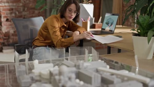 Two Young Diverse Architects Discussing Notes in Office