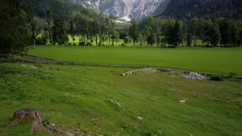Clouds above mountains and meadows with trees in front, pristine rural landscape of European Alps, J