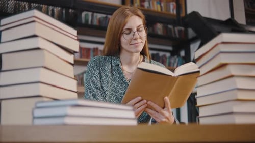 Young Woman Student or Businesswoman Reading a Book in the Library Students in a Good Mood Studying