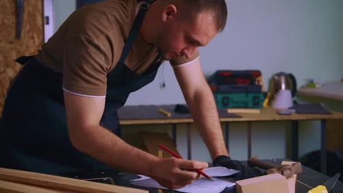 Carpenter Drawing Sketch on Paper in Workshop