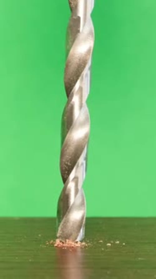 A Steel Drill on a Green Background is Used to Drill Holes in Wood
