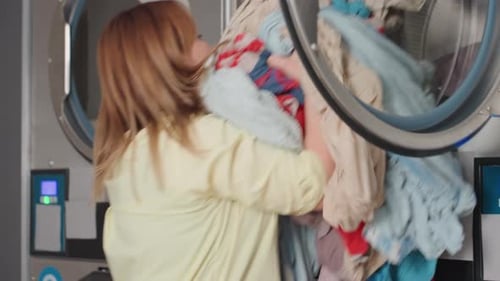 Le propriétaire de la buanderie transfère les vêtements de la laveuse au compartiment supérieur de la sécheuse