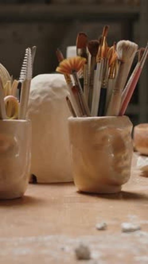 Vertical de vases en céramique et éléments de décoration sur un bureau dans un atelier de poterie sombre